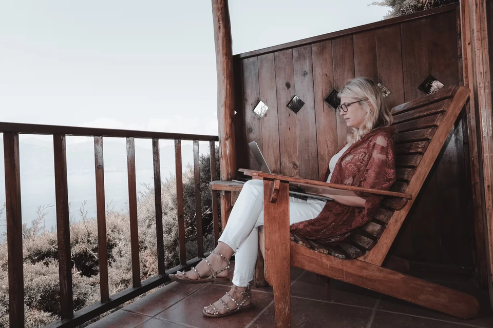 A woman working on a laptop on a balcony.