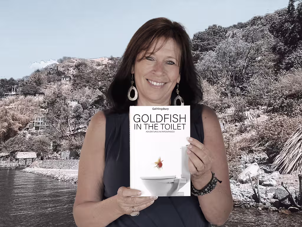 An author holding Goldfish in the Toilet beside a lake