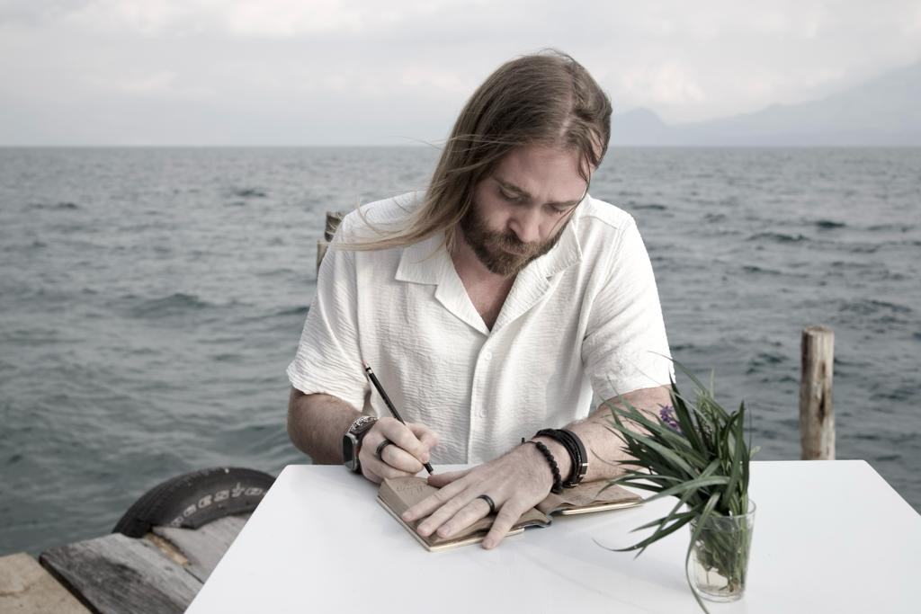 Michael R. Drew writing in a notebook beside the water