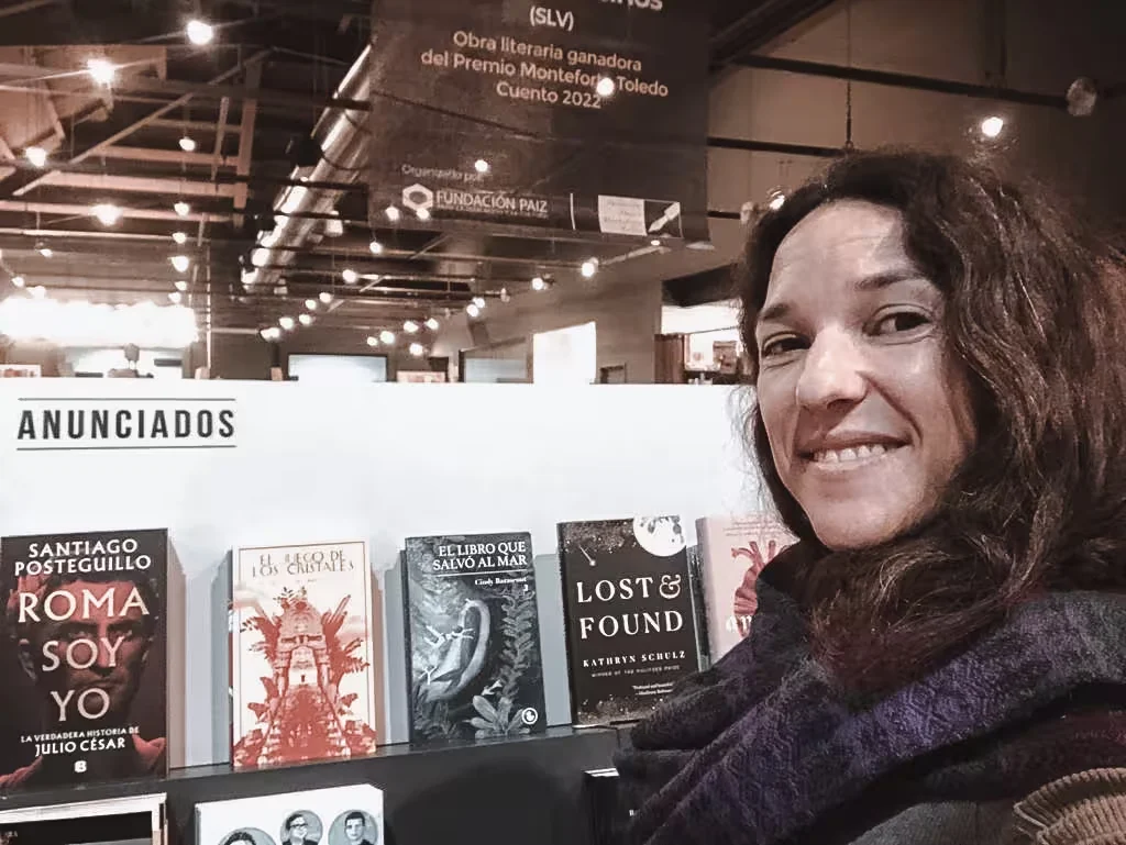 A visitor at a book fair beside shelves of published titles.